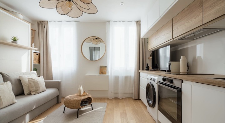 A bright, fully furnished studio: sofa, rattan lamp, oak floor and fitted kitchen